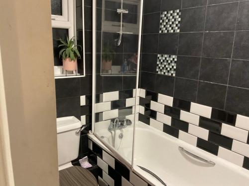 a bathroom with a black and white tiled wall at Comfy Double Room In Our Shared House in Palmers Green