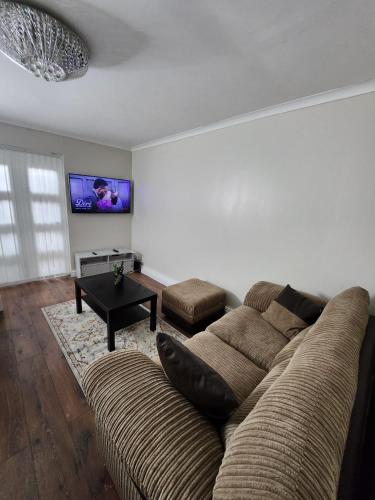 a living room with a couch and a tv at Home away from Home in Woolwich