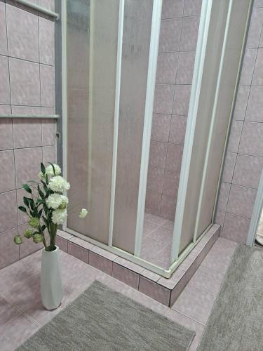 a vase with white flowers in a shower at Apartmani Bosna Visoko in Visoko