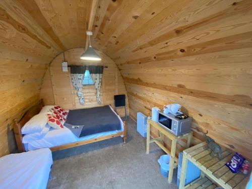 um quarto com uma cama e uma televisão num chalé de madeira em Rooms & Camping Pods at Colliford Tavern em Bodmin