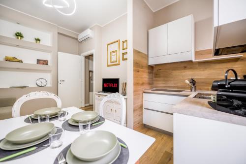 a kitchen with white cabinets and a table and chairs at Duomo a 10 minuti - Self check In Metro a 3 minuti a piedi in Milan