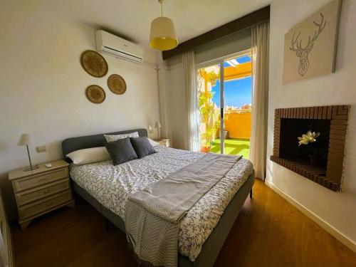 Un dormitorio con una cama y una ventana grande. en Apartment close to Marbella, en Cabopino