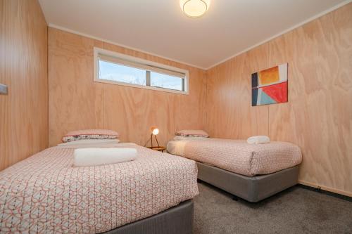 two beds in a room with wooden walls at Starbright Townhouse in Twizel