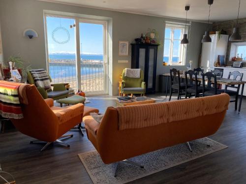 KópaskerにあるMelar Guesthouseのリビングルーム(オレンジ色のソファ、テーブル、椅子付)