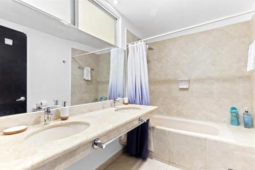uma casa de banho com uma banheira, um lavatório, uma banheira e um espelho. em 4 BR apartment, 8 guests em Cancún