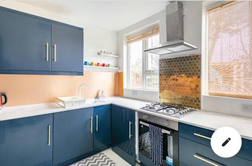 uma cozinha com armários azuis e um lavatório em Cheerful 3 bedroom entire home - newly furnished em Stockport