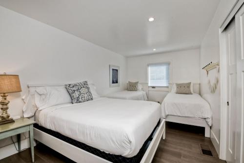 a white bedroom with two beds and a window at Luxury Ocean Views & Steps To The Sand - Tower 36 Lower Condo Unit in Carlsbad