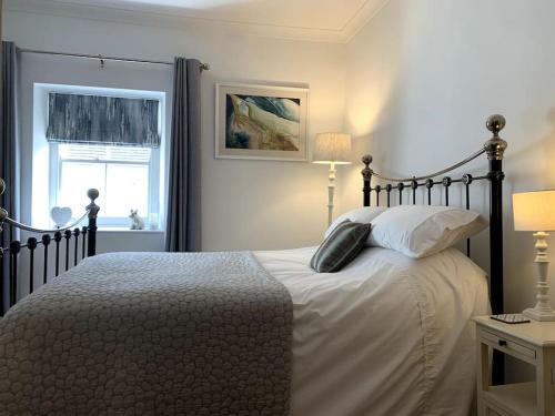 um quarto com uma cama grande com lençóis brancos e uma janela em The Vottage - 3 bed cottage em Plymouth