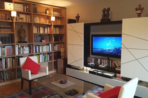 a living room with a television and bookshelves at Appartement tout équipé pour 4per parking privatif in Suresnes