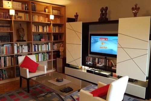 a living room with a tv in a library at Appartement tout équipé pour 4per parking privatif in Suresnes