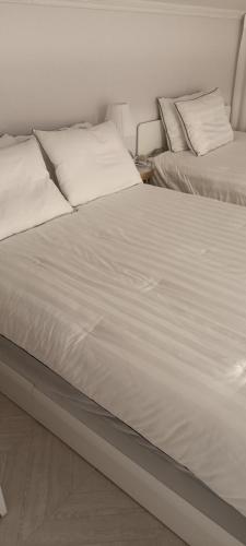 two beds in a bedroom with white sheets and pillows at Blooming Guest House in Daegu