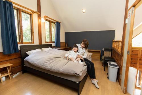 une femme et un enfant assis sur un lit dans l'établissement ログハウスkizuki, à Tsuru 