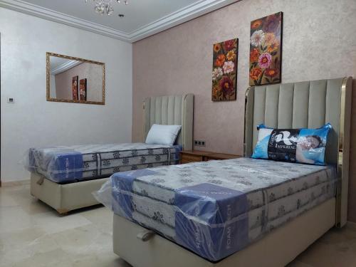 een slaapkamer met 2 bedden en een spiegel bij Residence La corniche Étage 2 in Nador