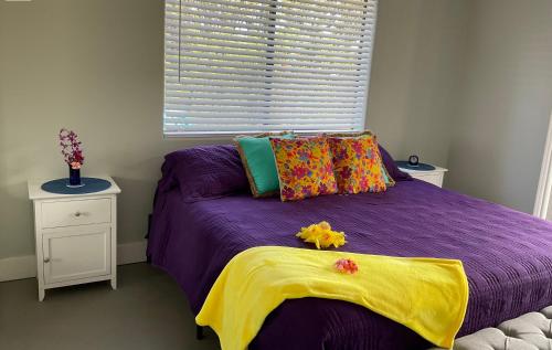 1 dormitorio con cama morada y ventana en The Art Garden- Hibiscus Guesthouse, en Hawaiian Ocean View