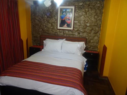 a bedroom with a large bed with a stone wall at Hostal Casa Del Inka in Cusco
