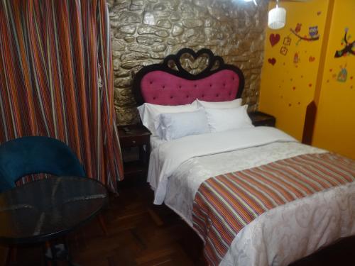 a bedroom with a king sized bed with a stone wall at Hostal Casa Del Inka in Cusco