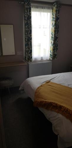 a bedroom with a bed and a window with curtains at Warner Lane in Selsey