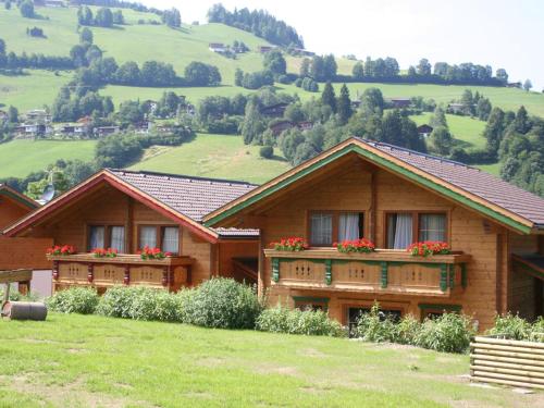 ニーデラウにあるChalet Wildschönauの2軒の木造家屋(窓に花箱付)