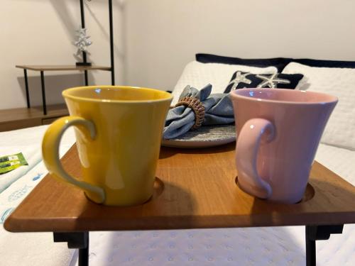 two coffee cups sitting on a wooden tray on a bed at BORA BORA RESIDENCE in Joinville