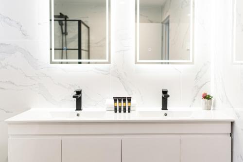 a white bathroom with two sinks and mirrors at Gosford Palms Motor Inn in Gosford