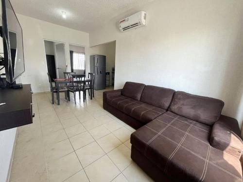 een woonkamer met een bruine bank en een tafel bij Condominio en Playa del Carmen c/alberca in Playa del Carmen