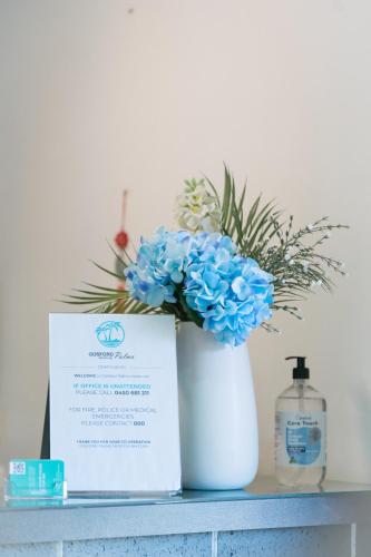a white vase with blue flowers sitting on a shelf at Gosford Palms Motor Inn in Gosford