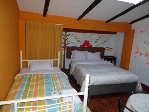 two beds in a bedroom with orange walls at Hostal Casa Del Inka in Cusco