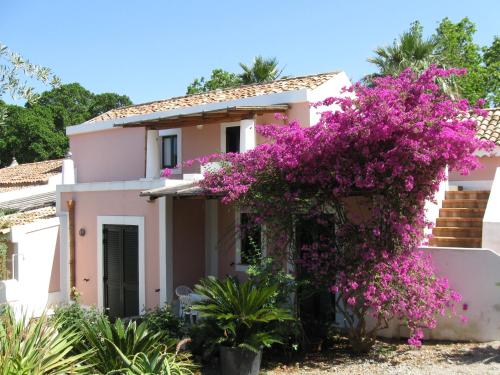dom z różowymi kwiatami przed nim w obiekcie Residence il Baglio w mieście San Giorgio