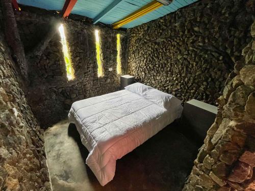 a bedroom with a bed in a stone wall at Cabaña Parque Arvi vista panorámica in Medellín