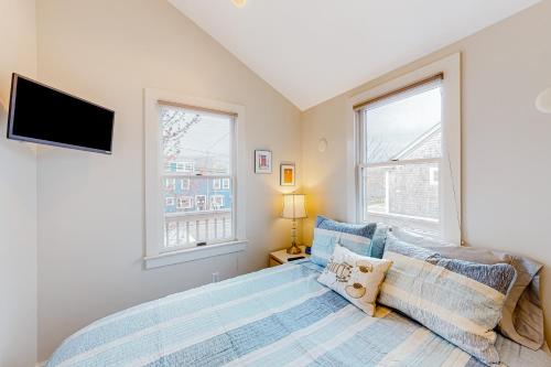 a bedroom with a bed and a tv and two windows at The Bradford Bistro in Provincetown