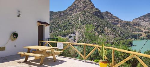 a wooden table and bench on a balcony with a mountain at La Barbería de Miguel in El Chorro