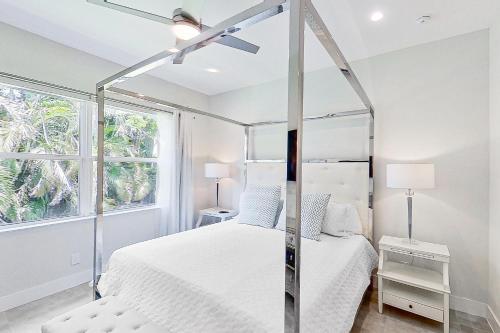 a white bedroom with a canopy bed and a window at The Blue Coral in Naples