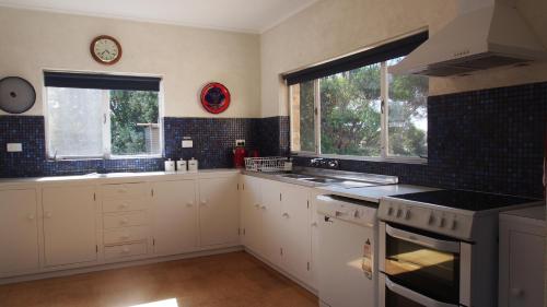 a kitchen with white cabinets and a clock on the wall at Ratcliff Cottage in Pelican Lagoon