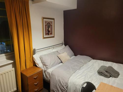 a small bedroom with a bed with white sheets at OneFourSeven Place in Manchester