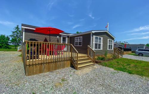 a small house with a deck and a red umbrella at Falcon Cottages in Niagara on the Lake