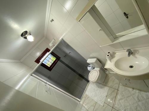 een witte badkamer met een wastafel en een toilet bij Casa Temporada Monte Belo do Sul in Monte Belo