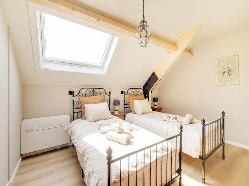 two beds in a attic bedroom with a window at Luxurious 5-star house in Limburg with jacuzzi, a paradise for families in Bree