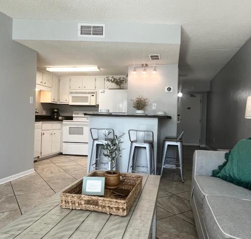 a living room and kitchen with a couch and a table at Condo on the Beach- walk to restaurants, shops and activities. in Gulf Shores