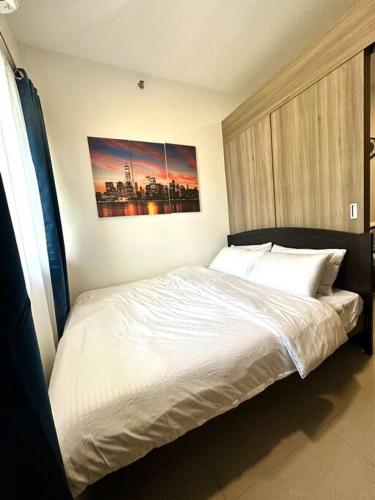 een slaapkamer met een wit bed en een schilderij aan de muur bij Modern 1-BR Condo Unit in Manilla