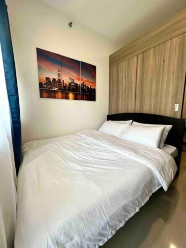 een slaapkamer met een wit bed en een schilderij aan de muur bij Modern 1-BR Condo Unit in Manilla