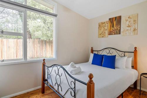 a bedroom with a bed with blue pillows and a window at Green Leaf Retreat/Central to Mountain Attractions in Wentworth Falls