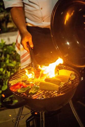 a person cooking food in a grill with flames at Nusa dua Ocean View with Private Beach in Nusa Dua