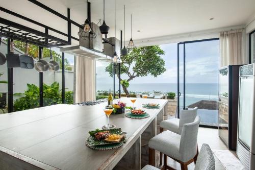 a dining room with a table and chairs with a view of the ocean at Cliff front luxury Olala Nusadua Beach in Nusa Dua
