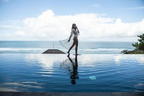 a woman standing in the water near the ocean at Nusa dua Ocean View with Private Beach in Nusa Dua