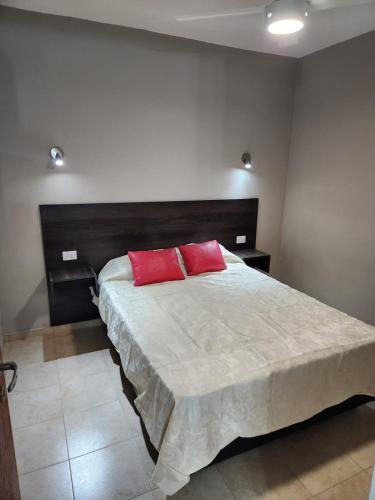um quarto com uma cama grande e 2 almofadas vermelhas em Departamento Capital II em La Rioja