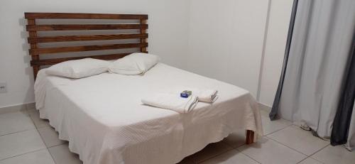 a small bed with white sheets and towels on it at Apartamento aconchegante in Ribeirão Preto