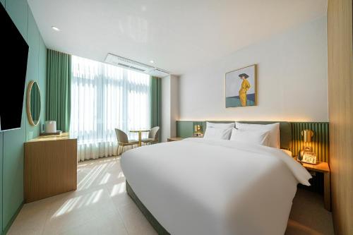 Un dormitorio con una gran cama blanca y una mesa en H-Avenue Hotel Geomdan New Town en Incheon