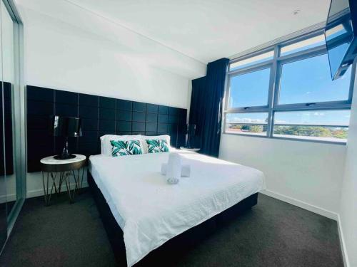 Un dormitorio con una gran cama blanca y una ventana en Sydney Executive Apartment 3beds2baths parking Chatswood, en Sídney