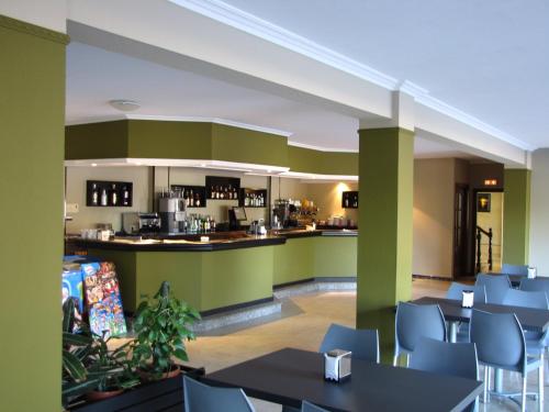 un restaurante con paredes verdes, mesas y sillas en Duerming Montalvo Playa Hotel, en Montalvo