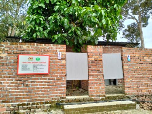 un mur en briques avec deux signaux blancs sur celui-ci, dans l'établissement CABIN CRYSTAL HONEY D ' RUMAH BONDA RIVER VIEW, à Kampong Senawar